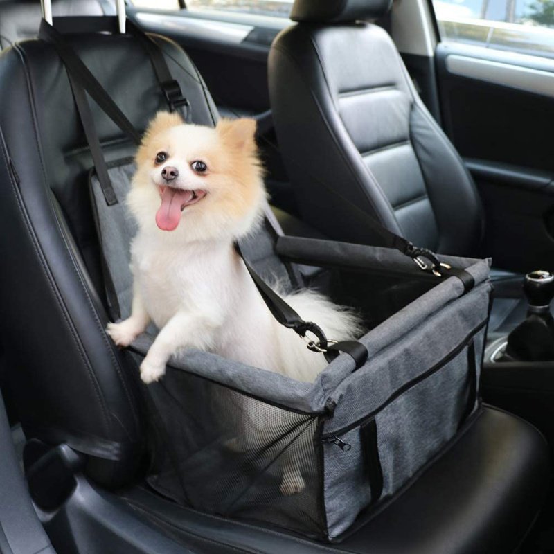 A dog sitting comfortably on a waterproof hammock-style car seat protector during a road trip.