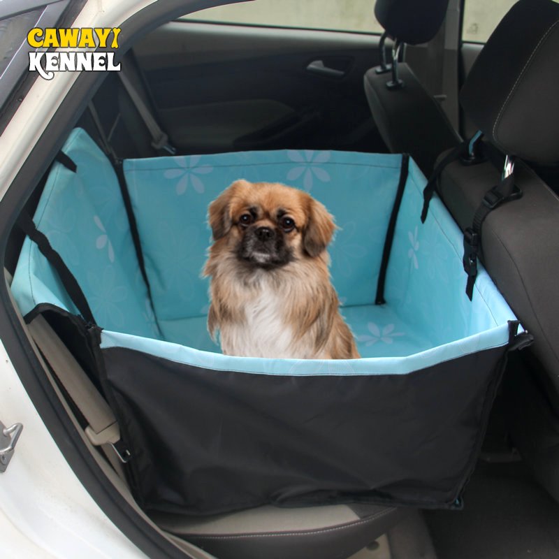 A dog sitting comfortably on a waterproof hammock-style car seat protector during a road trip.
